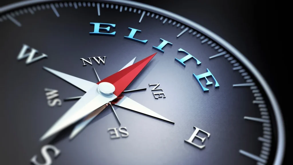 Close-up view of the face of a compass with its indicator pointing “north” directly at the word “Elite.”