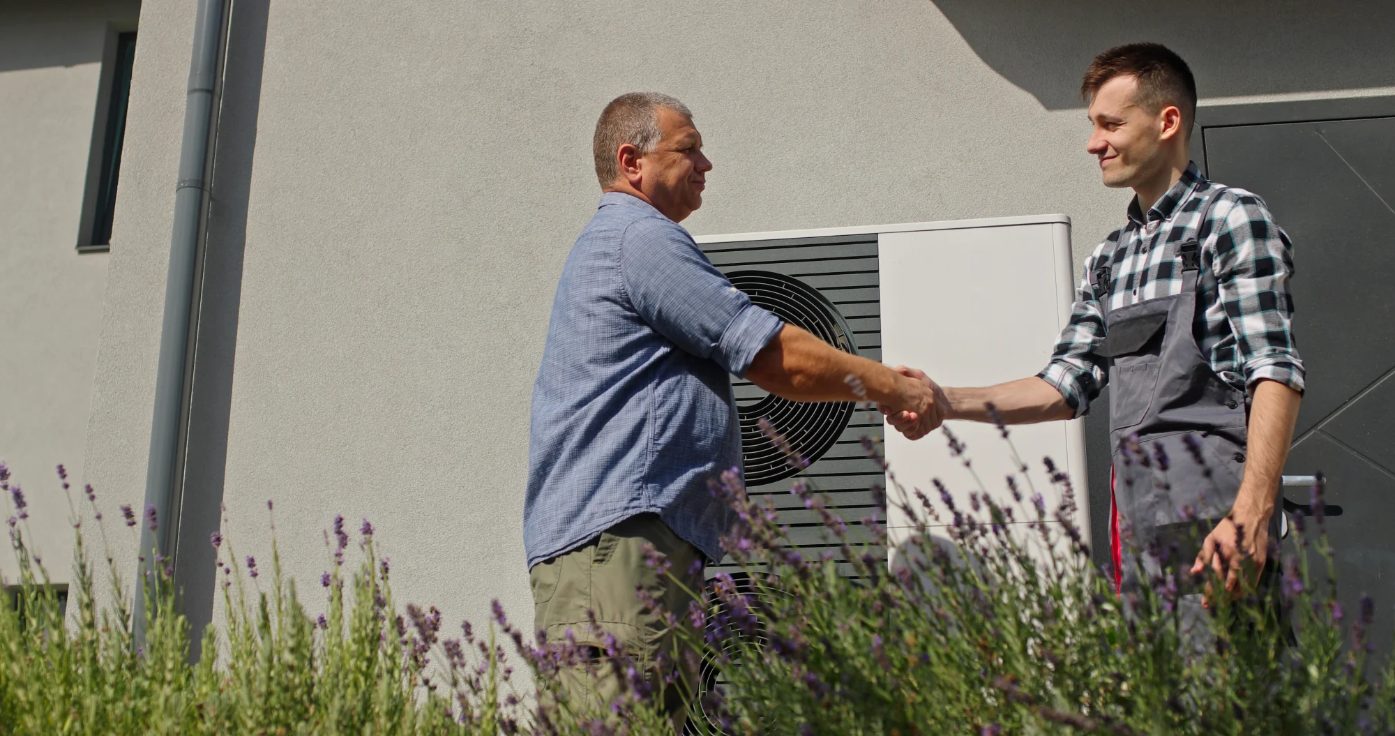 A homeowner shaking hands with an HVAC technician after replacing his HVAC system.